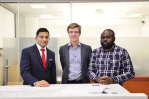 Drs. Amit Garg, Peter Blake and Flory Muanda standing together a a high table.