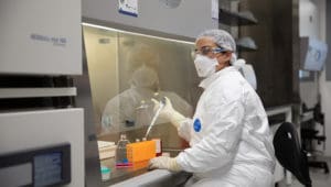 Worker in full personal protective gear works inside level 3 containment facility at western