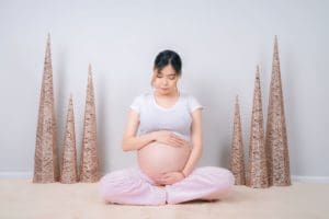 woman-showing-her-baby-bump-while-sitting-on-floor