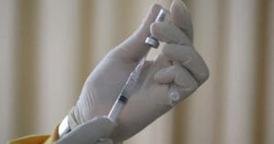 Gloved hands holding a vaccine